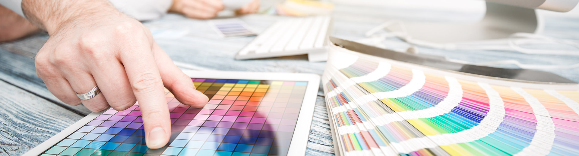Corporate design: zet je design goed in de markt Bureau met mensen die werken aan corporate design met computer en kleurwaaier